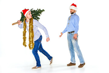 Image showing The young man in Santa cap carrying Christmas tree