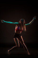 Image showing Young beautiful dancer in beige dress dancing on black background