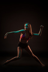 Image showing Young beautiful dancer in beige dress dancing on black background