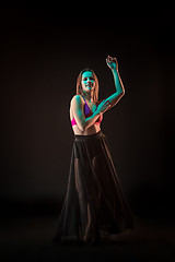 Image showing Young beautiful dancer in beige dress dancing on black background