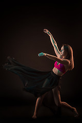 Image showing Young beautiful dancer in beige dress dancing on black background