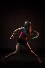 Image showing Young beautiful dancer in beige dress dancing on black background