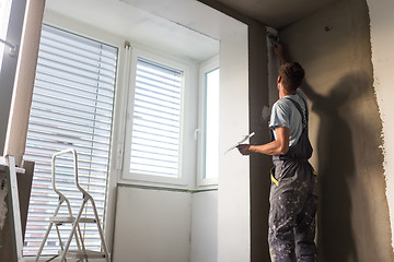 Image showing Plasterer renovating indoor walls and ceilings. Construction finishing works.