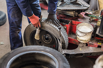 Image showing Professional auto mechanic replacing tire on wheel in car repair service.