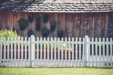 Image showing White picket fence in front af a wooden shed