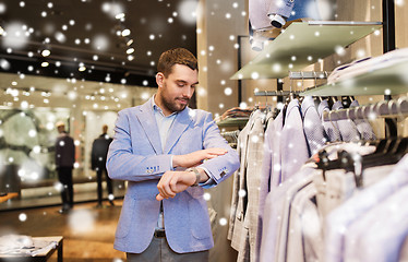 Image showing happy young man trying jacket on in clothing store