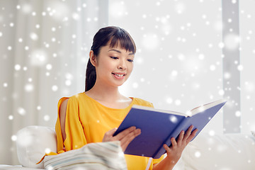 Image showing smiling young asian woman reading book at home