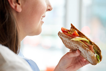 Image showing close up of happy woman eating panini sandwich