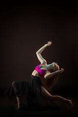 Image showing Young beautiful dancer in beige dress dancing on black background