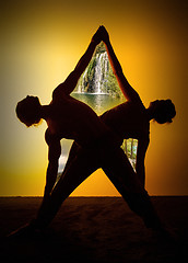 Image showing Two people practicing yoga in the sunset light