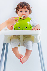 Image showing Happy baby boy sitting and eating