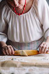 Image showing Making meat dumpling with wooden rolling pin.