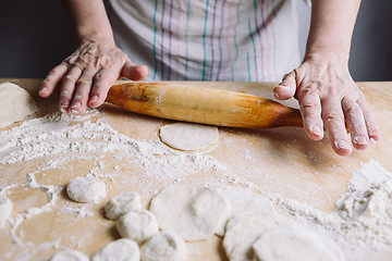 Image showing Making meat dumpling with wooden rolling pin.