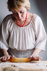 Image showing Making meat dumpling with wooden rolling pin.