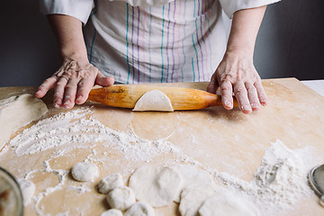 Image showing Making meat dumpling with wooden rolling pin.