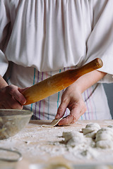 Image showing Making meat dumpling with wooden rolling pin.