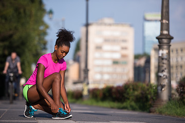 Image showing African american woman runner tightening shoe lace