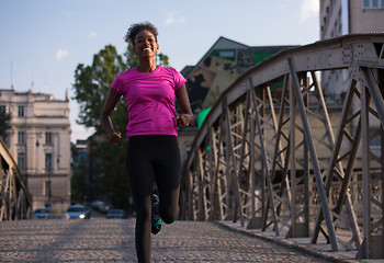 Image showing african american woman running across the bridge