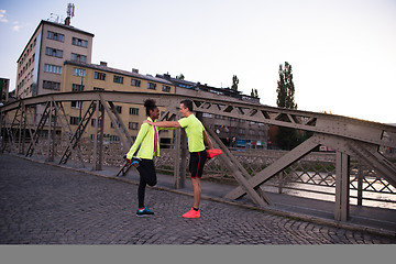 Image showing jogging couple warming up and stretching in the city