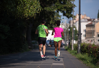 Image showing young smiling multiethnic couple jogging in the city