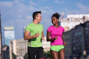 Image showing young smiling multiethnic couple jogging in the city