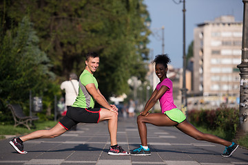 Image showing jogging couple warming up and stretching in the city