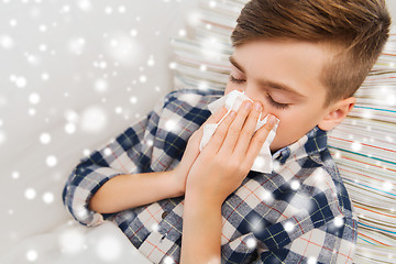 Image showing close up of ill boy lying in bed and blowing nose