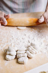 Image showing Making meat dumpling with wooden rolling pin.