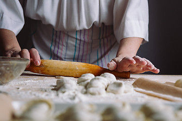 Image showing Making meat dumpling with wooden rolling pin.