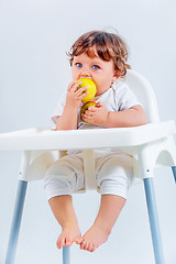 Image showing Happy baby boy sitting and eating