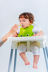 Image showing Happy baby boy sitting and eating
