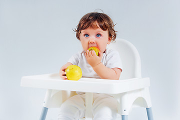 Image showing Happy baby boy sitting and eating