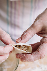 Image showing Two hands making meat dumplings.