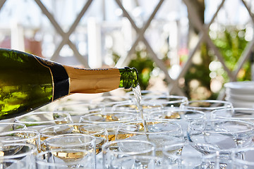 Image showing Pouring champagne in flutes standing on table