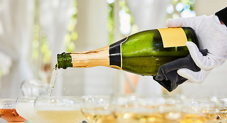 Image showing Pouring champagne in flutes standing on table