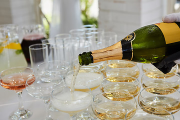 Image showing Pouring champagne in flutes standing on table