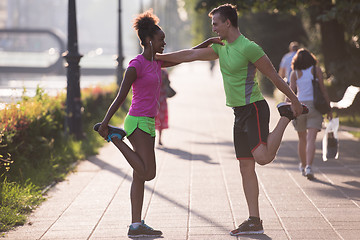 Image showing jogging couple warming up and stretching in the city