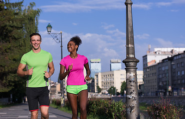 Image showing young smiling multiethnic couple jogging in the city