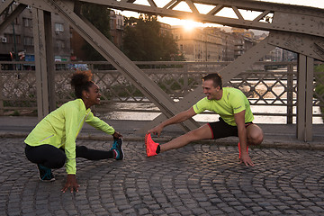 Image showing jogging couple warming up and stretching in the city