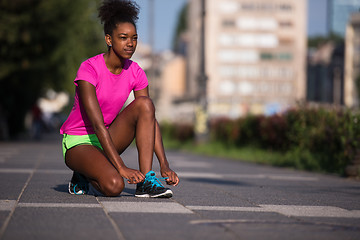 Image showing African american woman runner tightening shoe lace