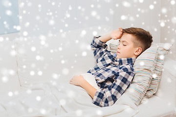 Image showing ill boy lying in bed and suffering from headache