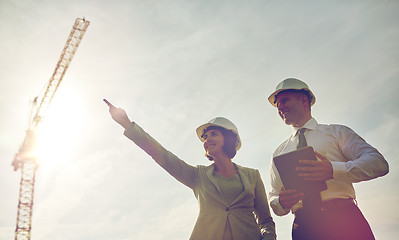 Image showing happy builders in hardhats with tablet pc outdoors