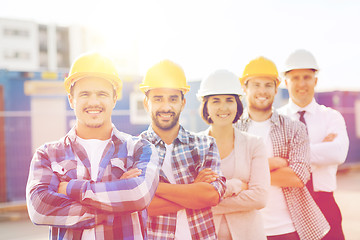 Image showing group of smiling builders in hardhats outdoors