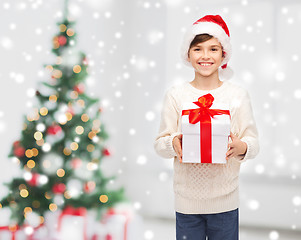 Image showing smiling happy boy in santa hat with gift box