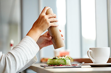 Image showing woman with salt shaker and salad at restaurant