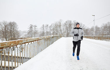 Image showing man running along snow covered winter bridge road