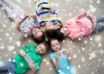 Image showing happy children with smartphones lying on floor