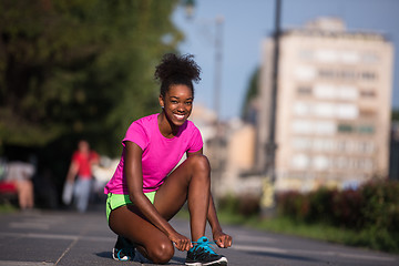 Image showing African american woman runner tightening shoe lace