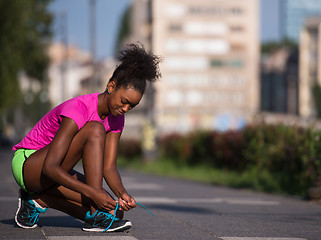 Image showing African american woman runner tightening shoe lace