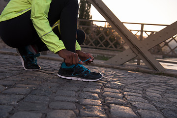 Image showing African american woman runner tightening shoe lace